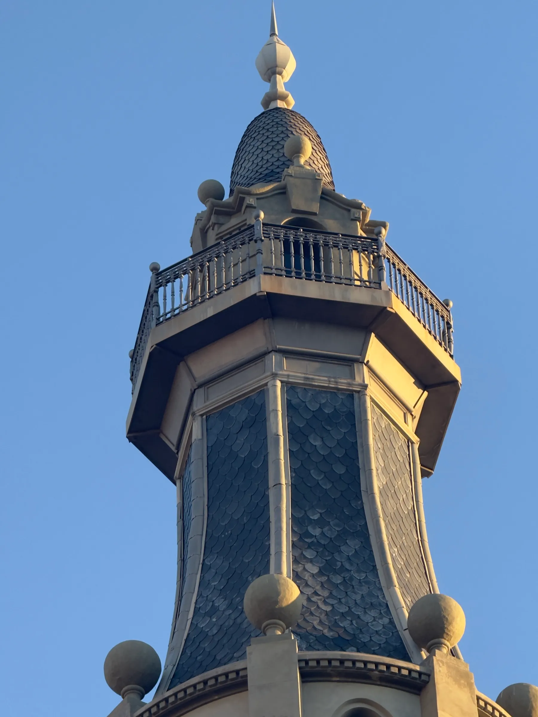 An ornate modernista street lamp seen from directly below against a blue sky.