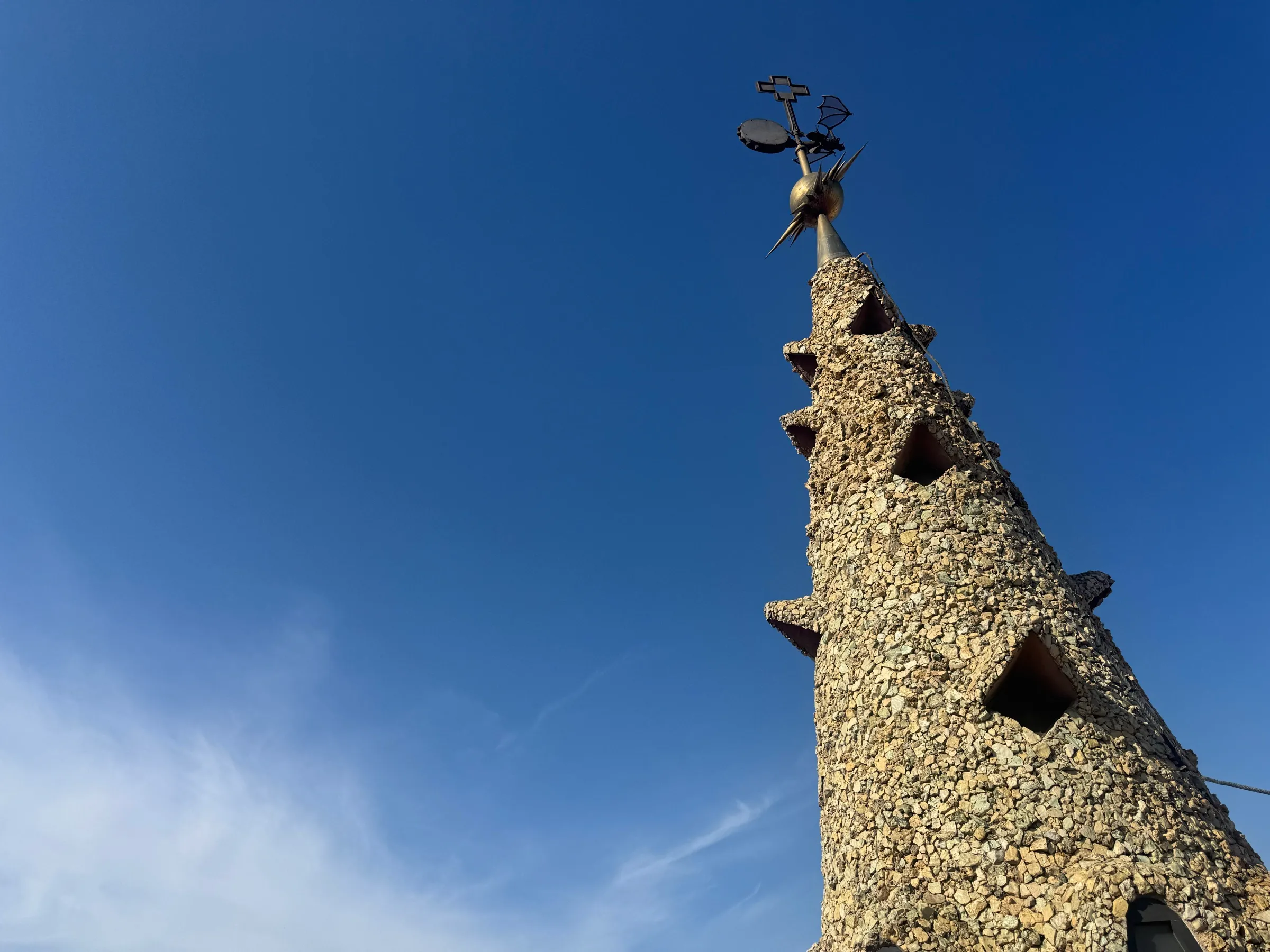 A tall stone spire with organic openings rising against the sky.