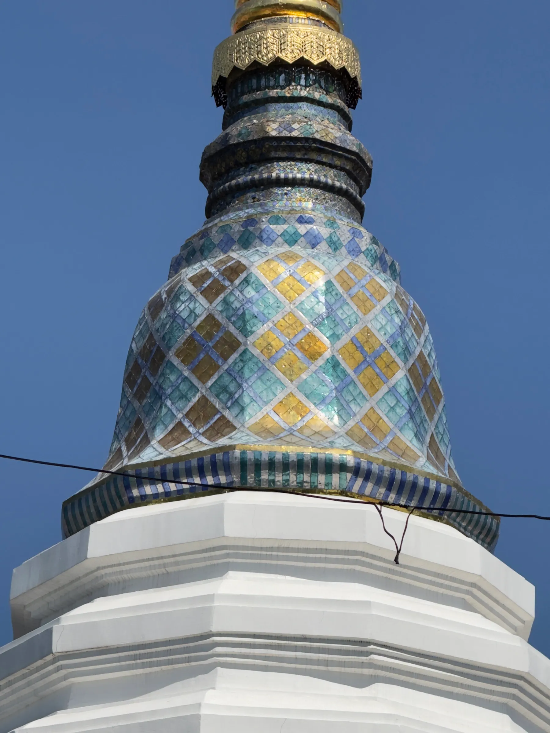 An ornate blue-tiled chedi spire seen from directly below.