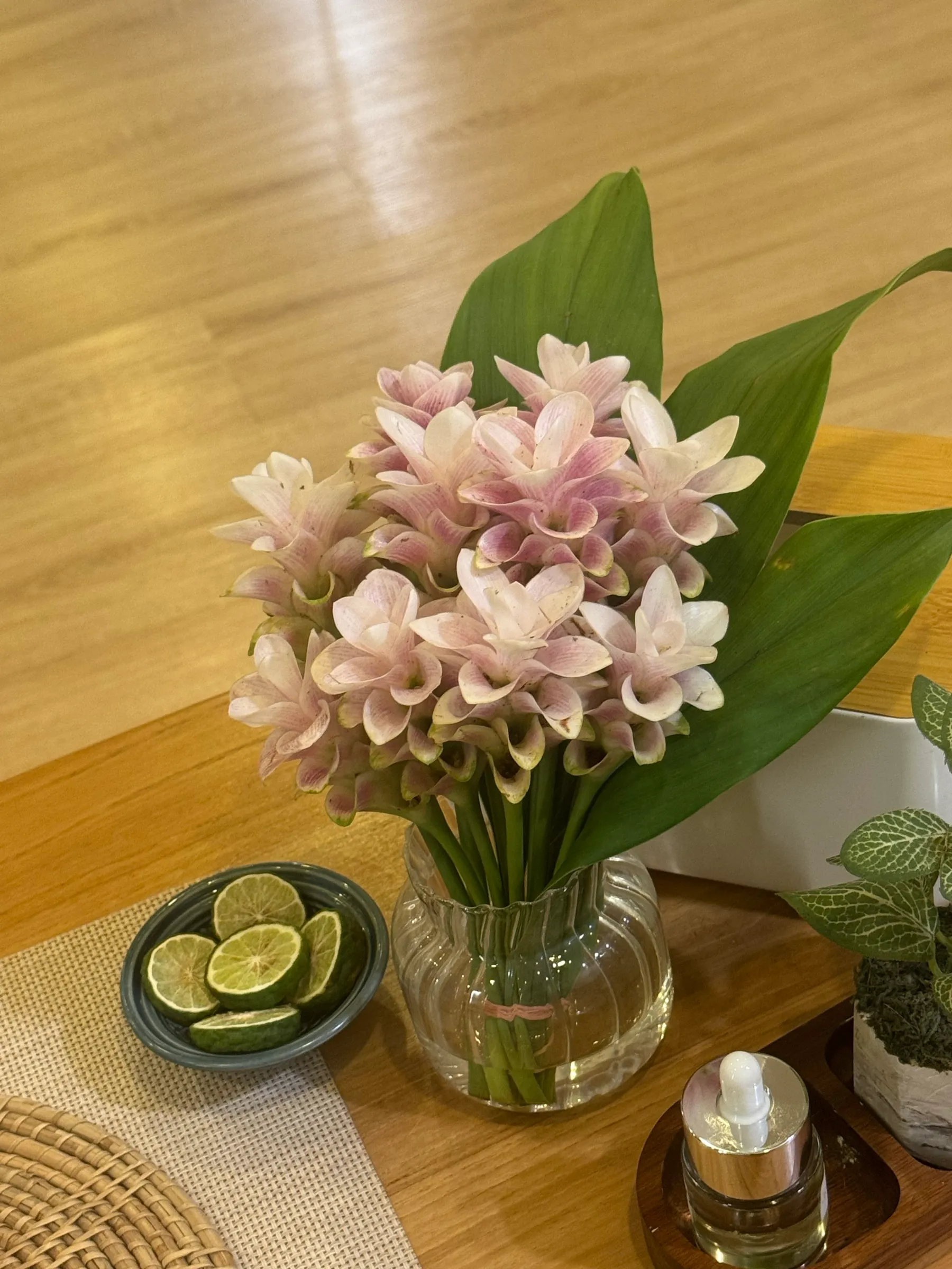 Pink flowers and cold drinks arranged on a light wood café table.